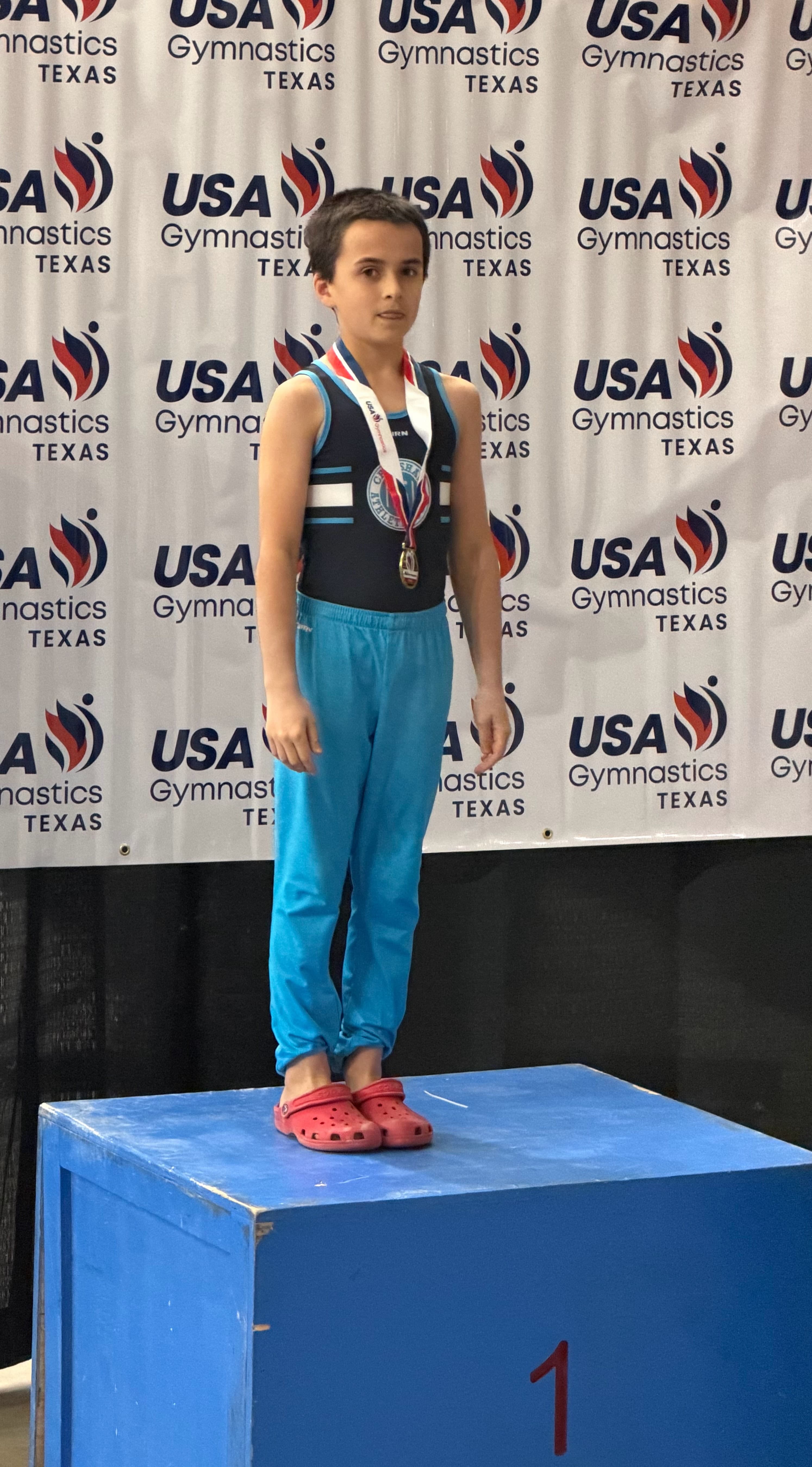 Lukas standing on the first-place podium with his medal.